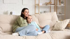 image credit canva stock image of woman sitting with daughter on sofa